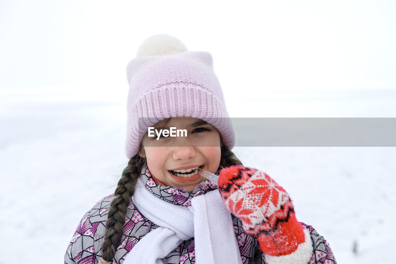 Portrait of smiling girl biting ice during winter