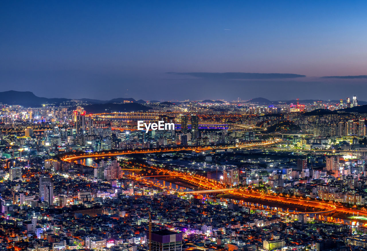 Aerial view of city at night against sky