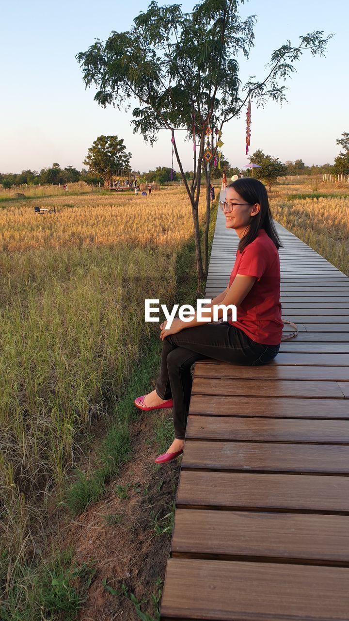 Young woman sitting by land on boardwalk