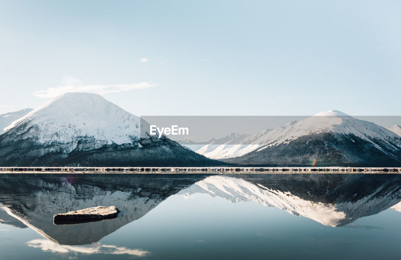 Snowcapped mountains reflecting on calm lake