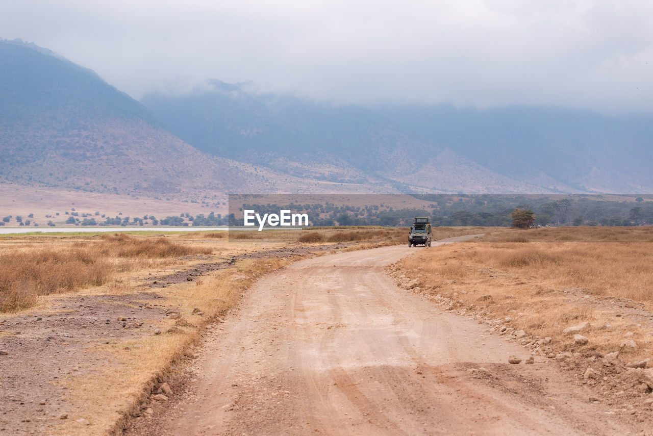 Dirt road on land against sky