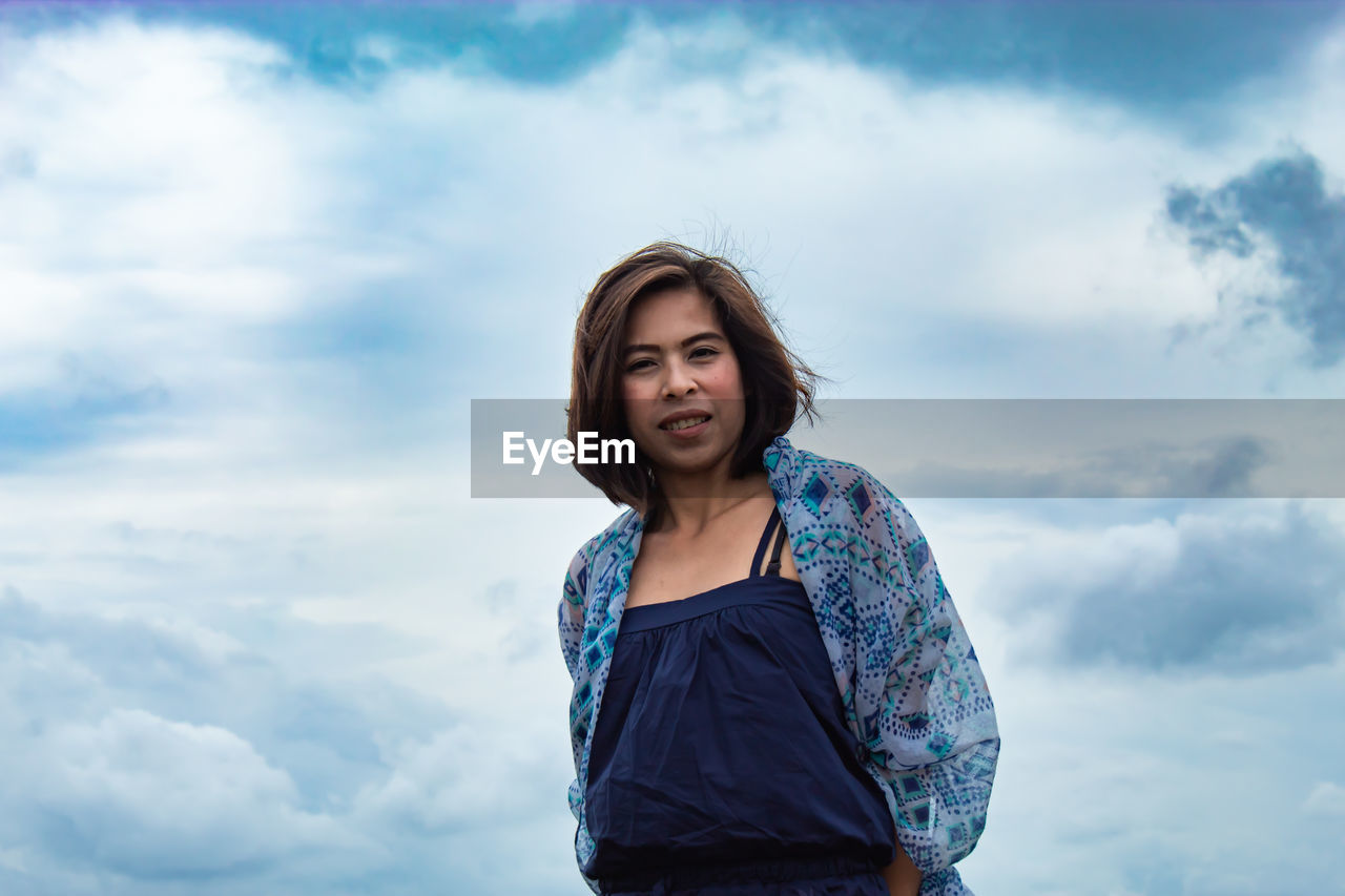 Portrait of beautiful young woman against sky