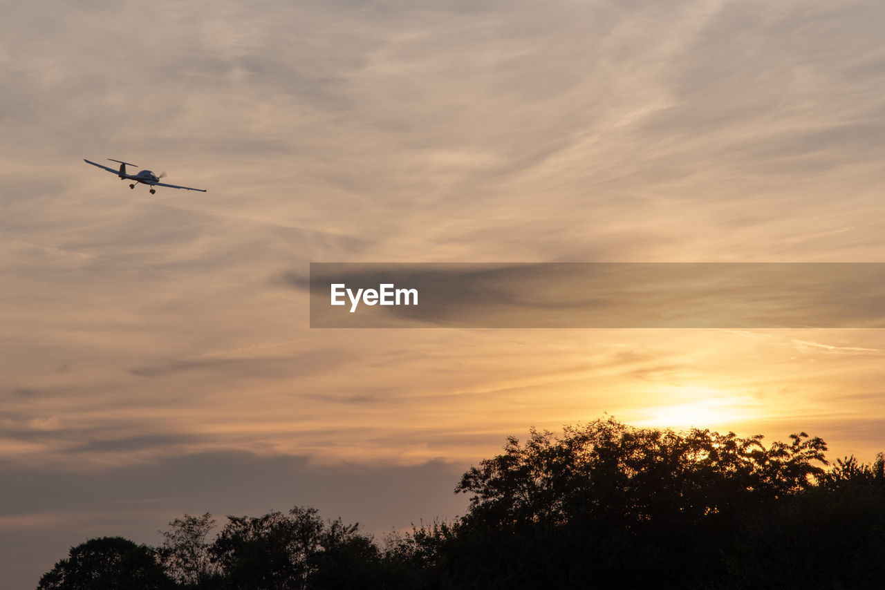 LOW ANGLE VIEW OF SILHOUETTE AIRPLANE AGAINST SKY DURING SUNSET