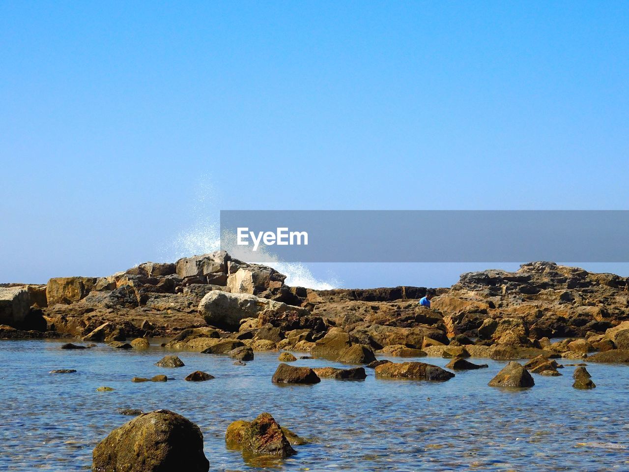 ROCKS ON BEACH AGAINST CLEAR SKY