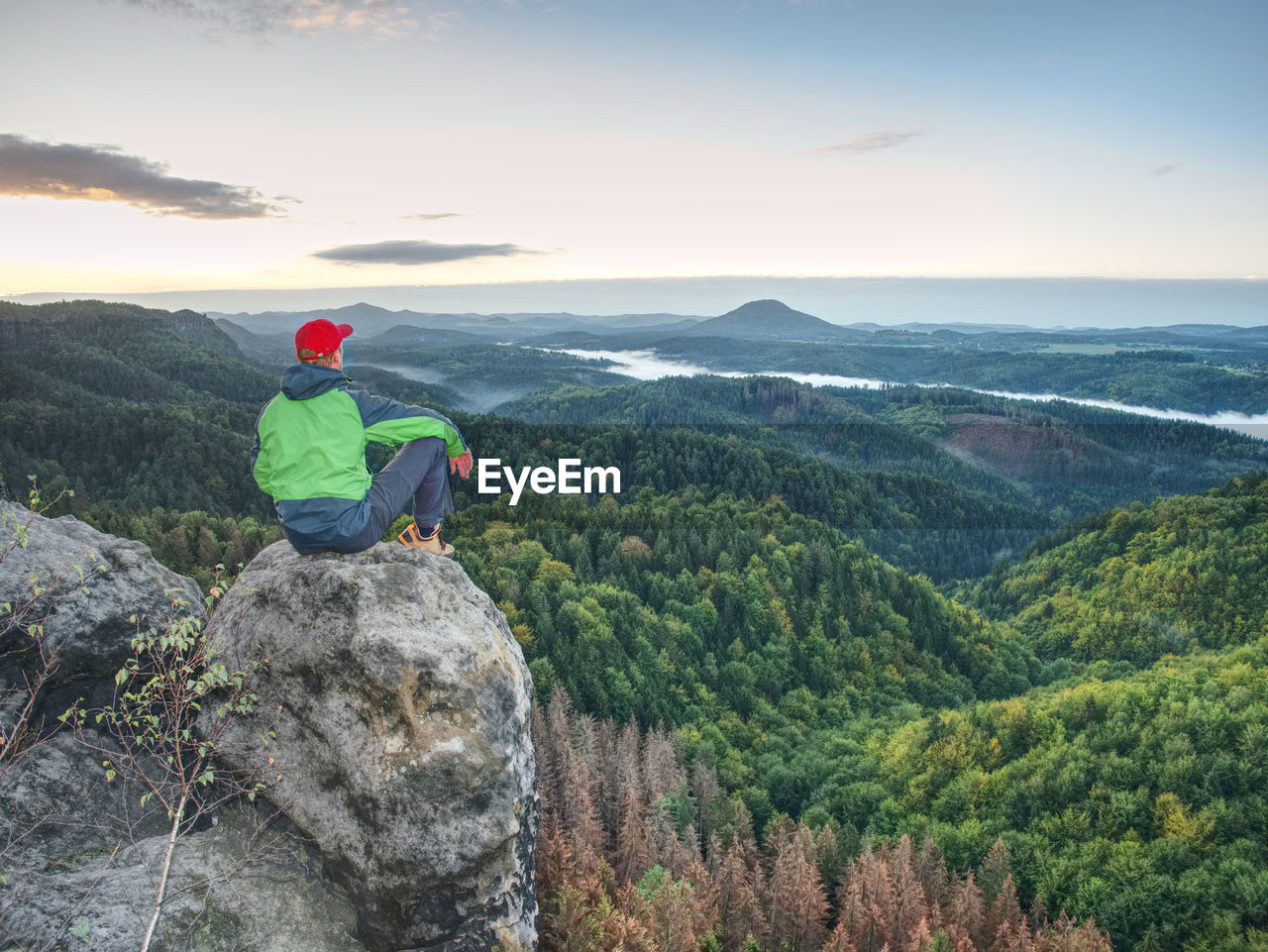 Moment of loneliness. man on the rock empires and watch over the misty landscape