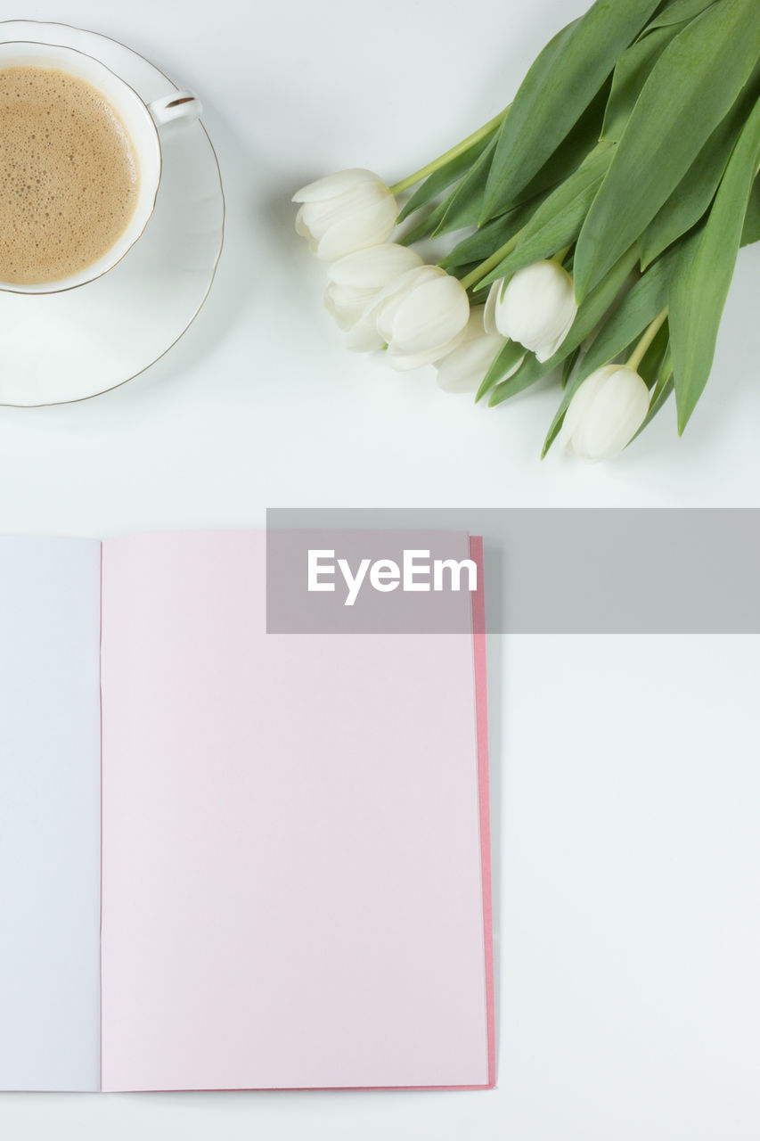 Directly above shot of coffee cup with flowers and book on table