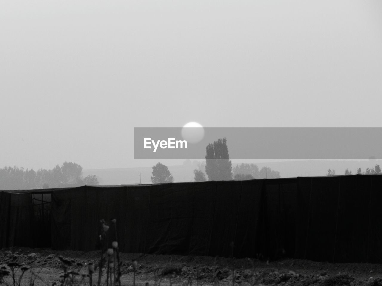 Field by built structure against sky during sunset