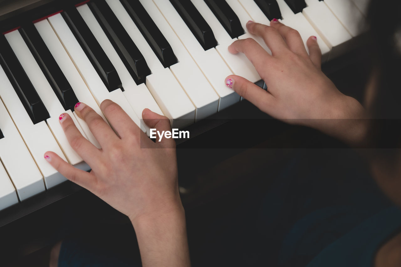 MIDSECTION OF WOMAN PLAYING PIANO AT HOME