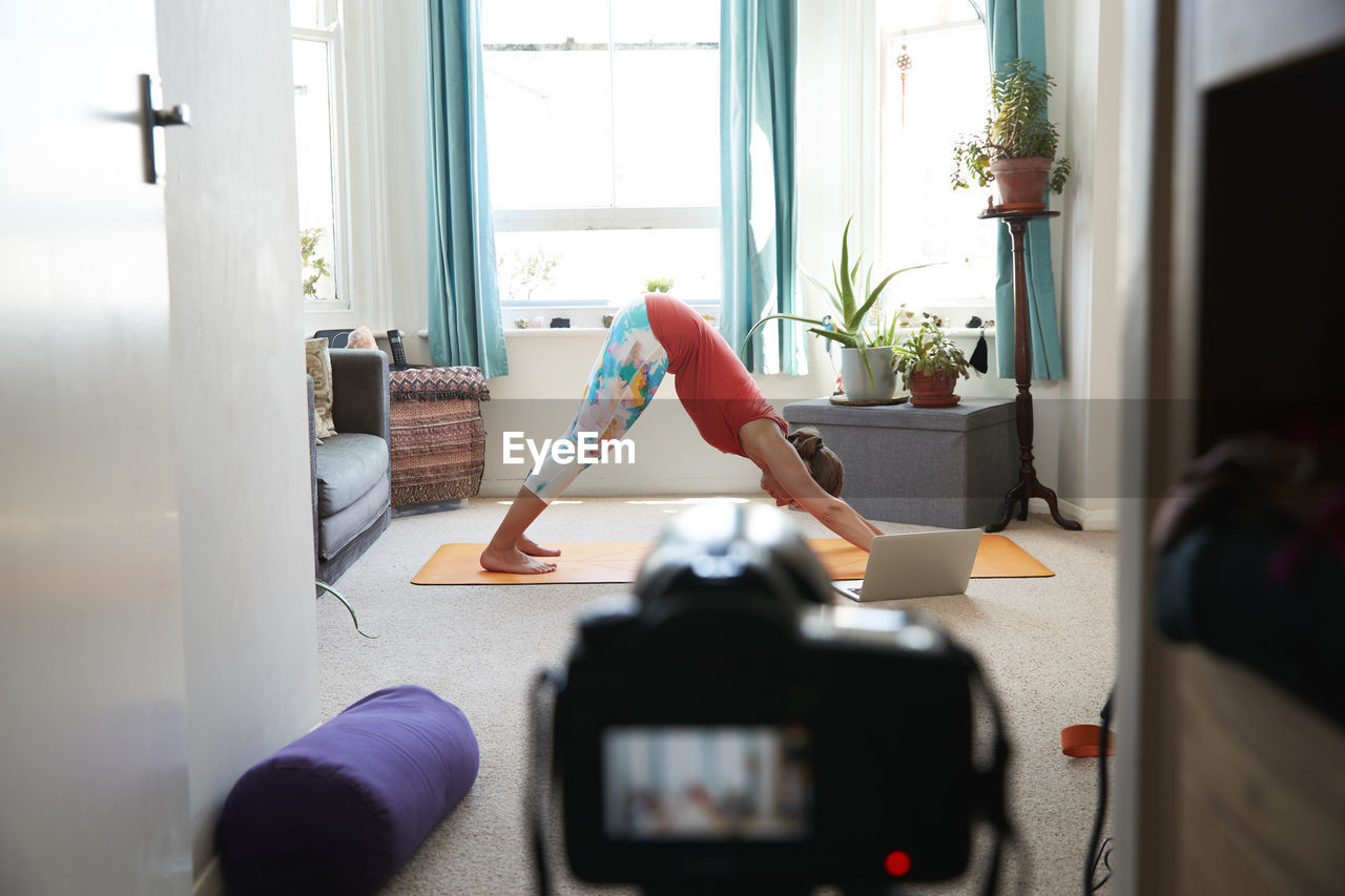 Female athlete doing exercise video recording with camera at home