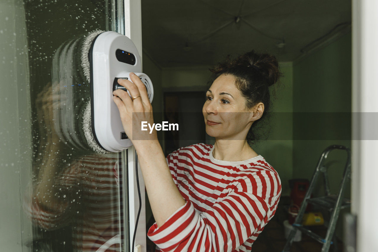 Woman cleaning window with robot washer