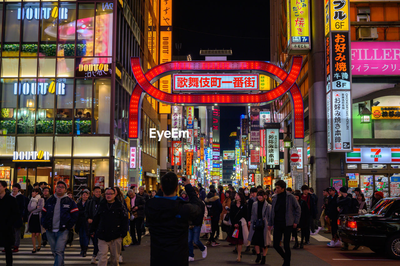 PEOPLE ON ILLUMINATED STREET AT NIGHT