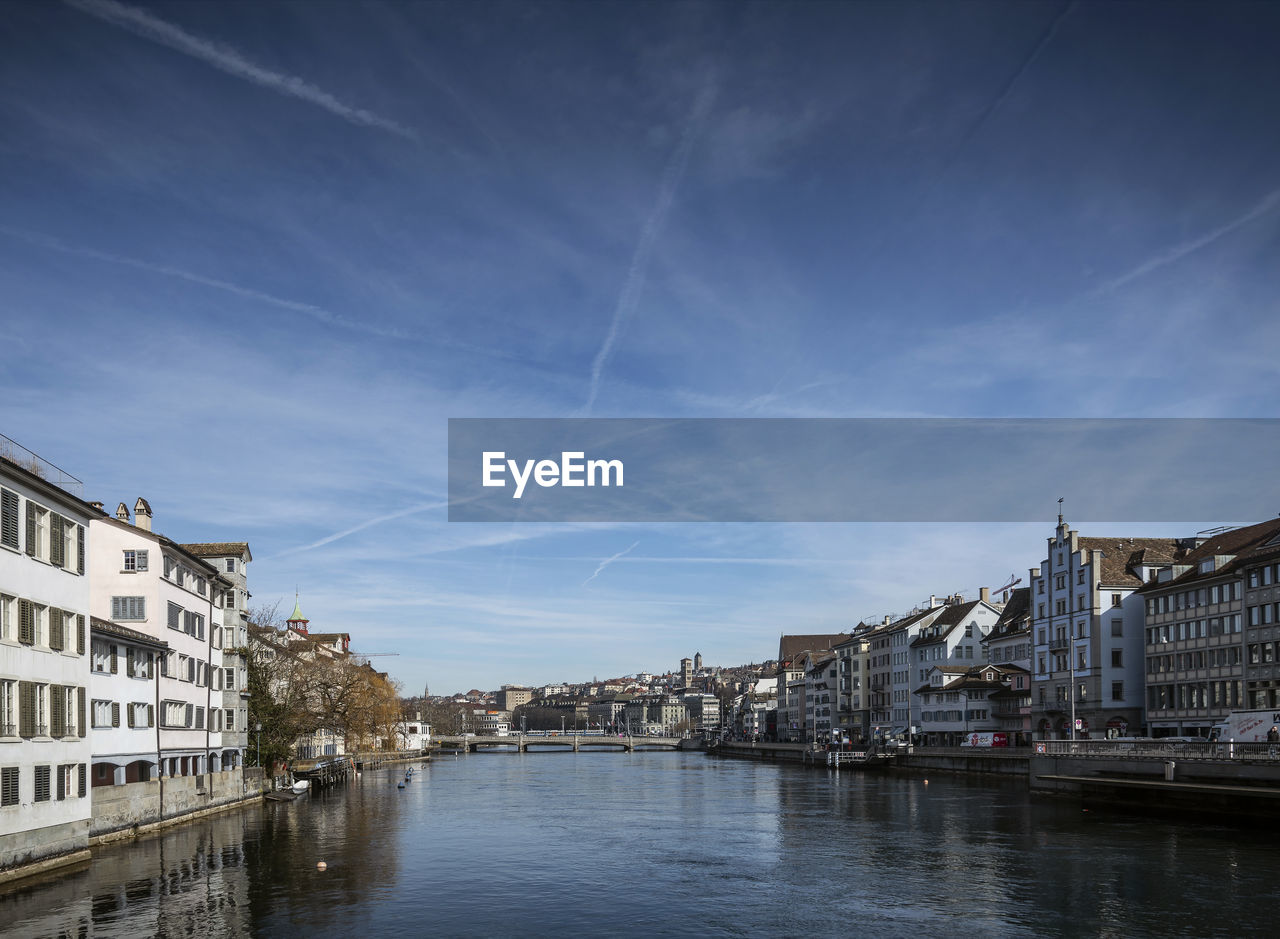 Canal by old building against sky in city