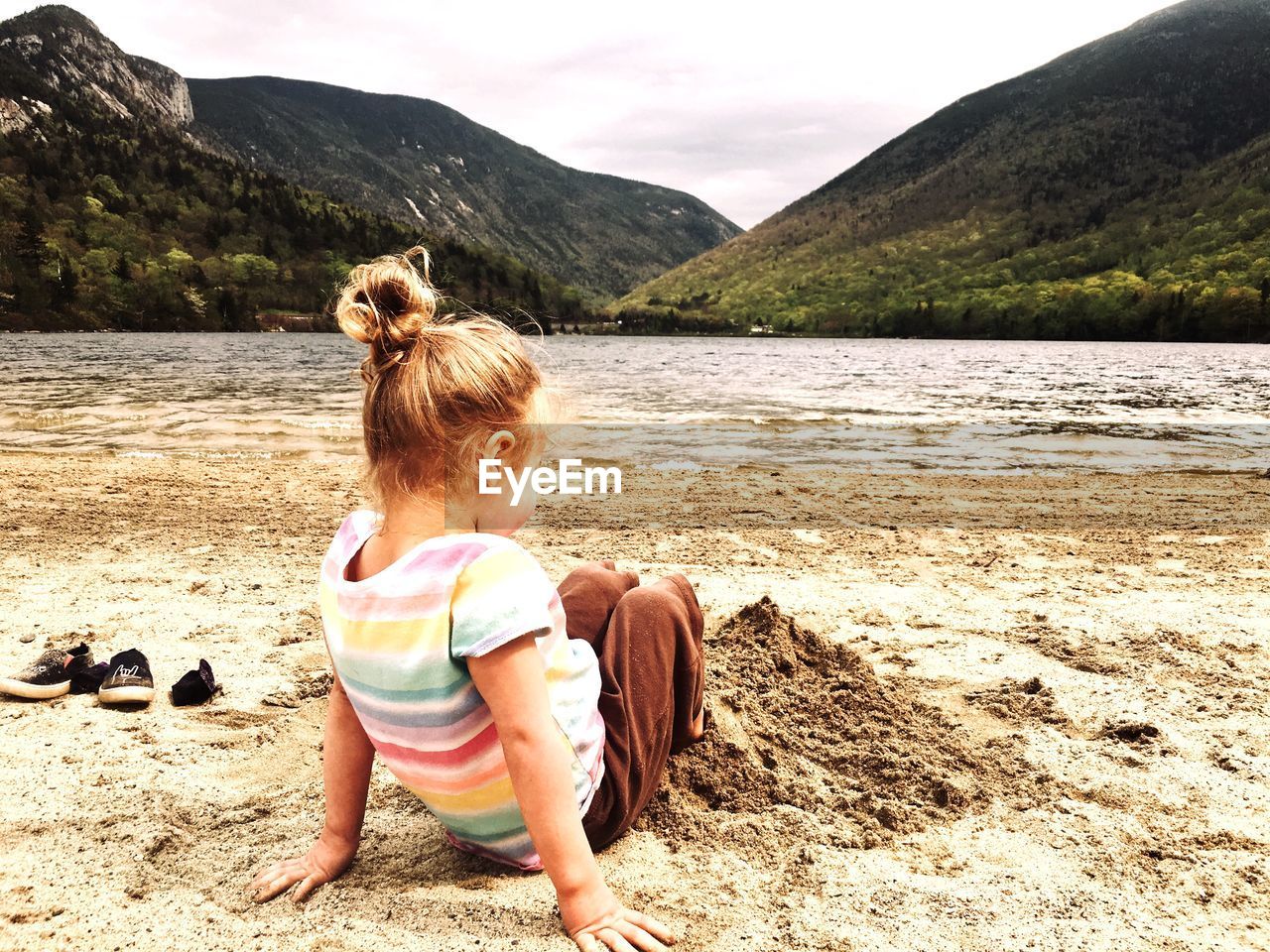 Full length of girl sitting on beach against sky