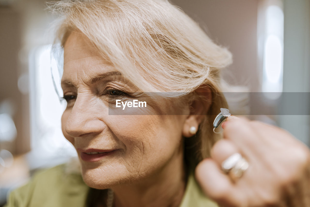 Senior woman applying hearing aid