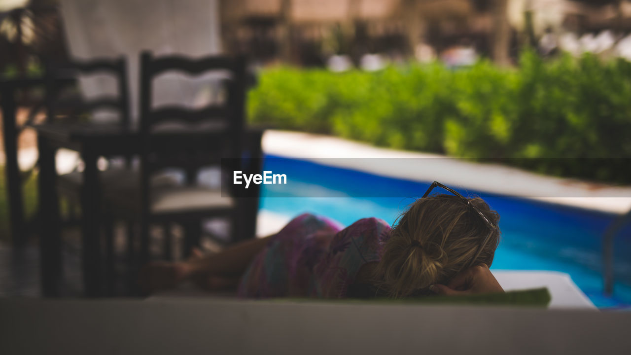 REAR VIEW OF WOMAN SITTING AT RIVERBANK