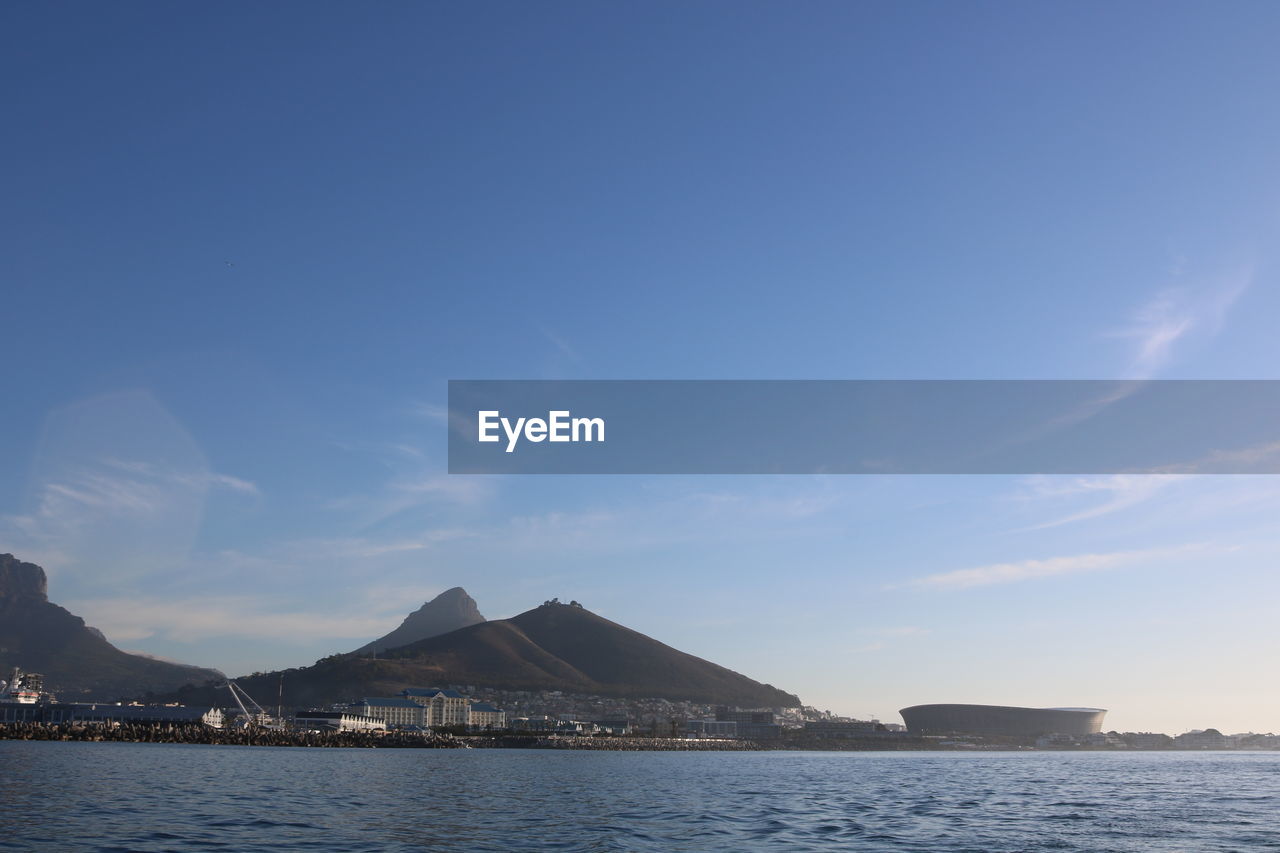 Scenic view of sea and mountains against blue sky