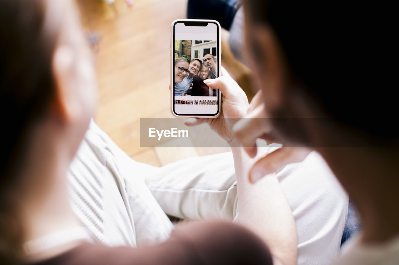 Siblings looking at family photo on smart phone