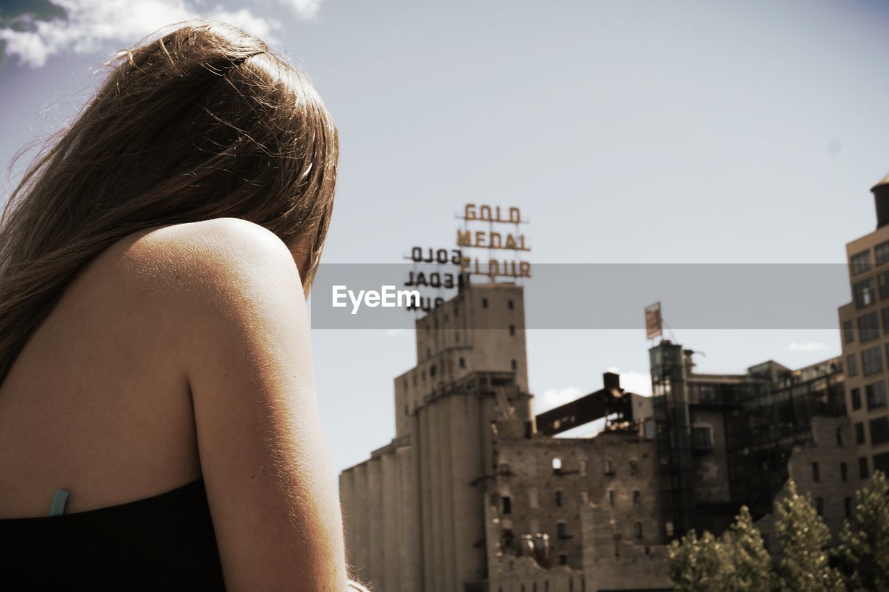 Rear view of woman looking away against buildings