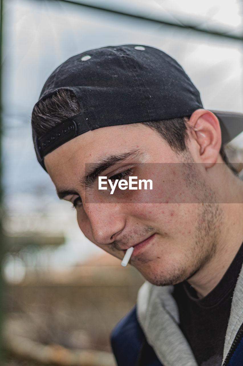 PORTRAIT OF YOUNG MAN LOOKING AWAY OUTDOORS