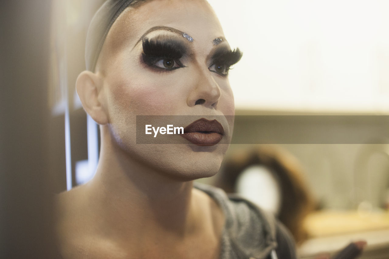 Young man applying drag makeup