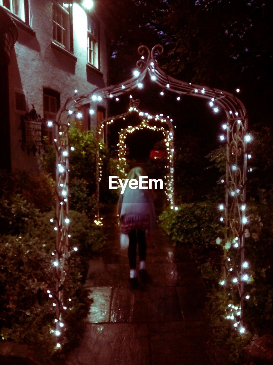 WOMAN STANDING IN ILLUMINATED CITY AT NIGHT