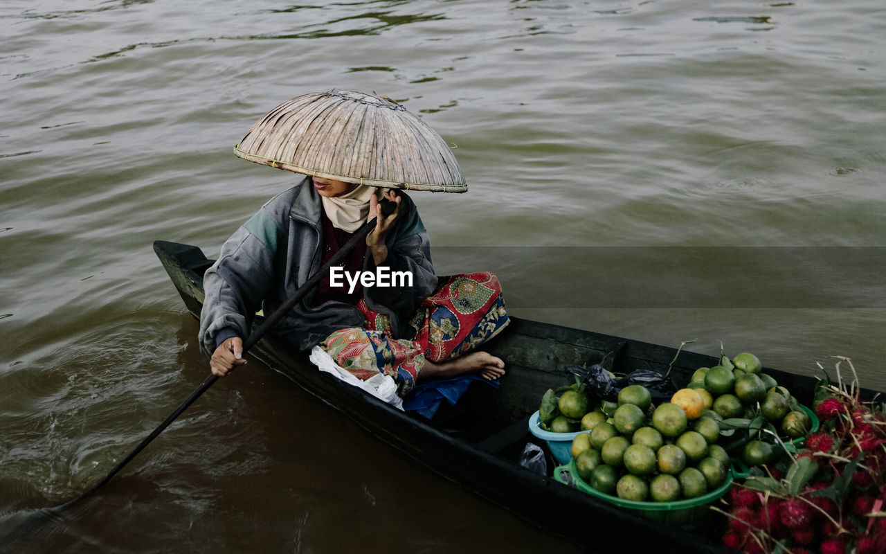High angle view of woman paddling boat with fruits in floating market