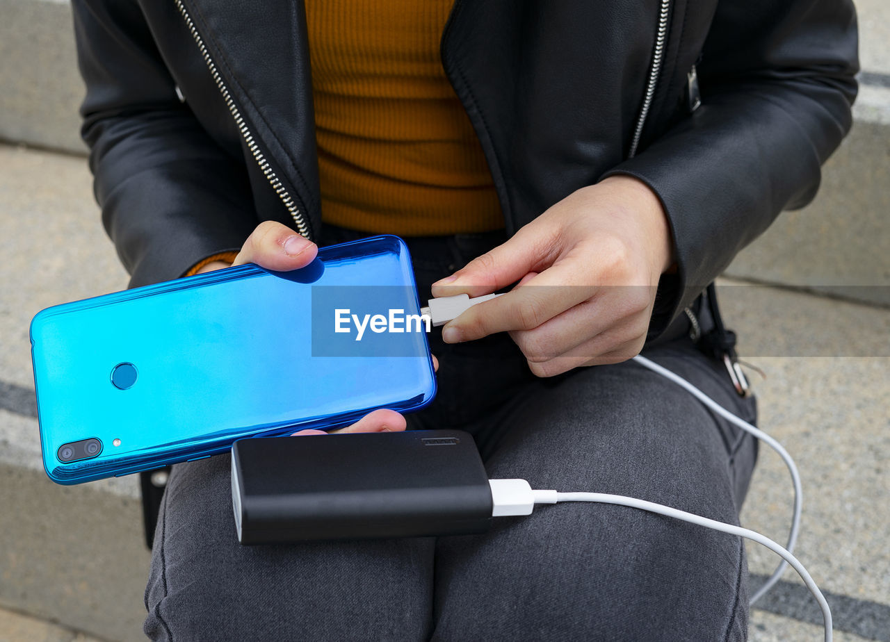 Woman connecting the mobile to a powerbank.