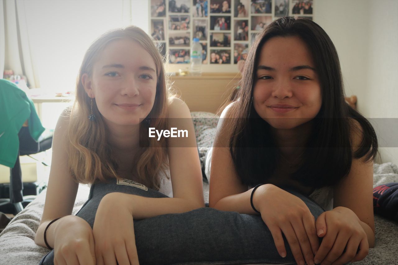 Portrait of smiling friends lying on bed at home