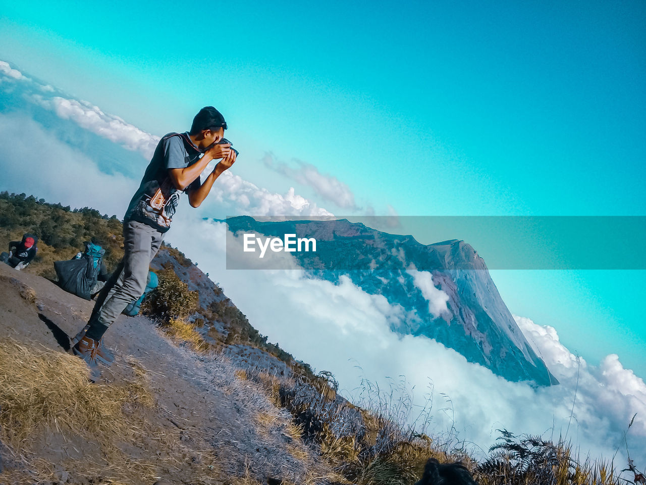 YOUNG MAN ON MOUNTAIN AGAINST SKY