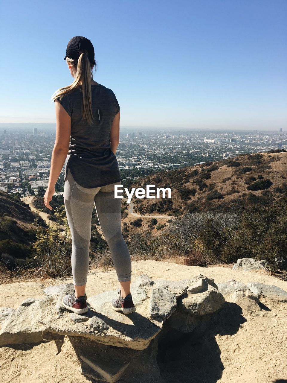 Young woman standing on rock against sky