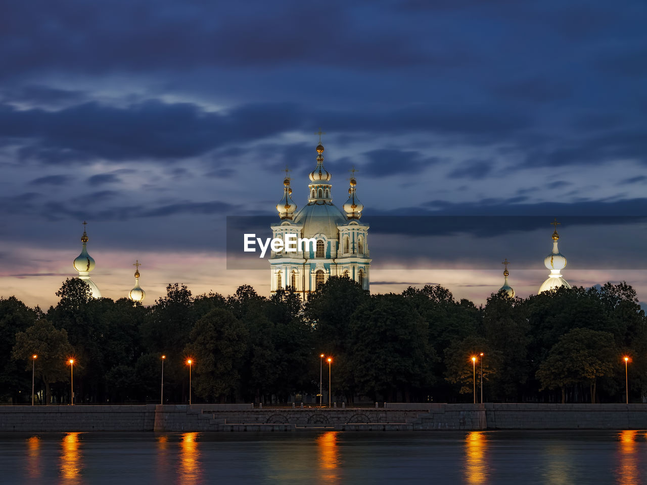 Illuminated cathedral against cloudy sky at dusk