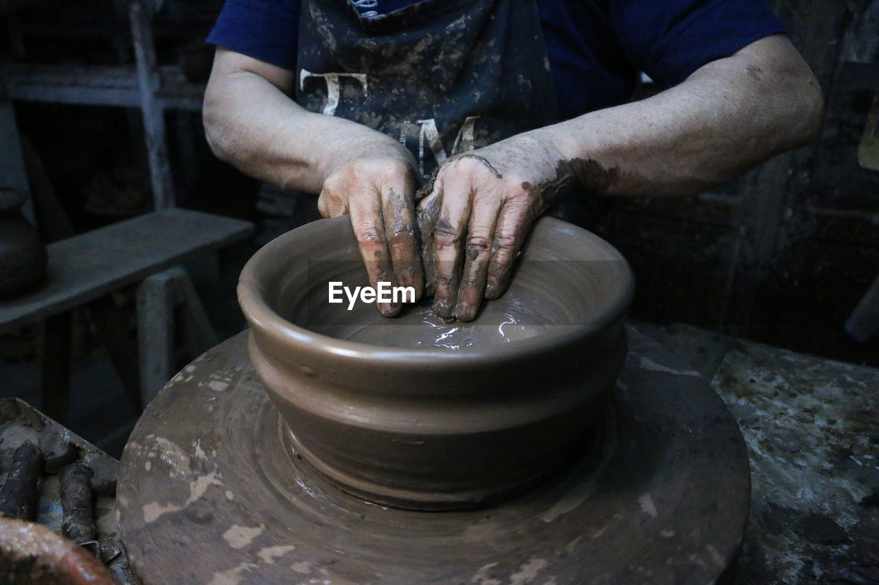 Midsection of man making pottery in workshop