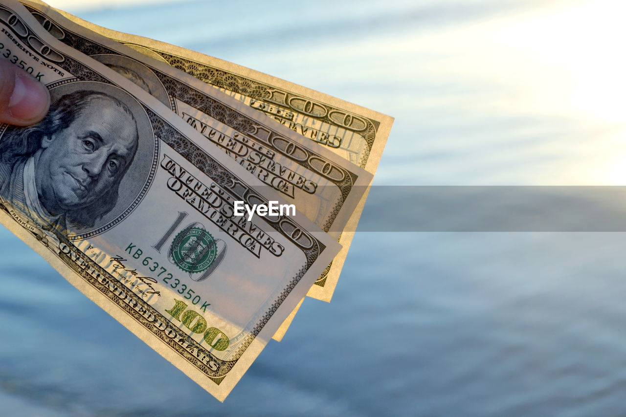 Three hundred dollar bills on background of sea surface. 100 dollar cash. concept success finance