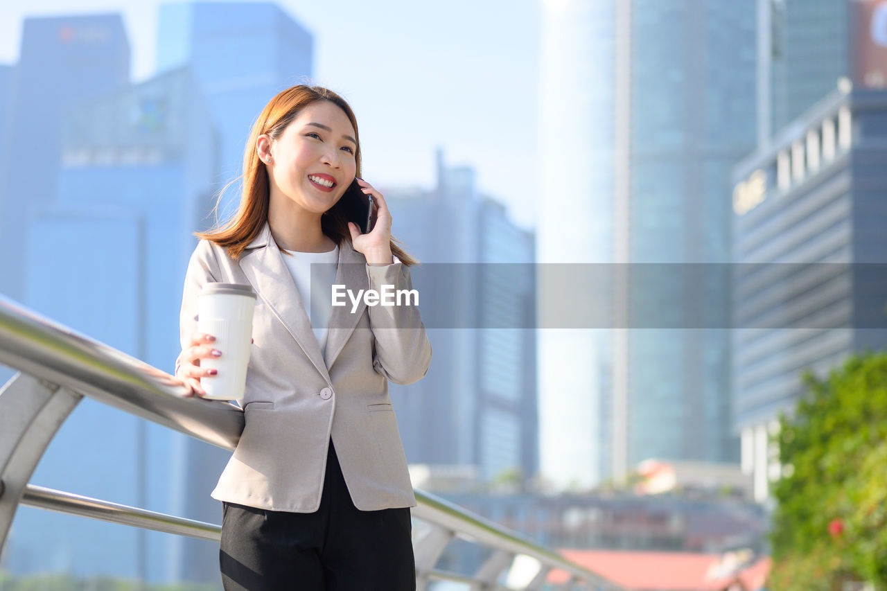 Businesswoman talking over phone while standing in city