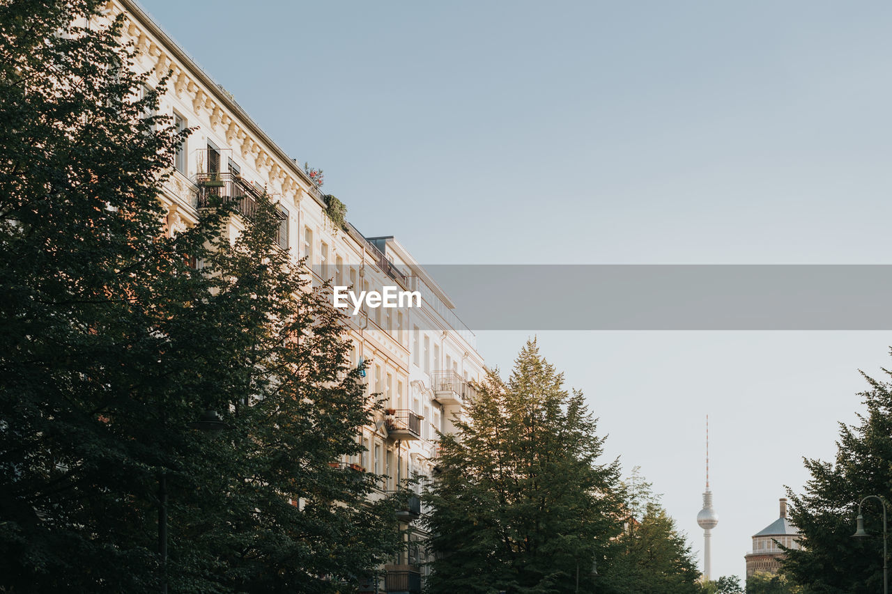 LOW ANGLE VIEW OF BUILDING BY TREES AGAINST SKY