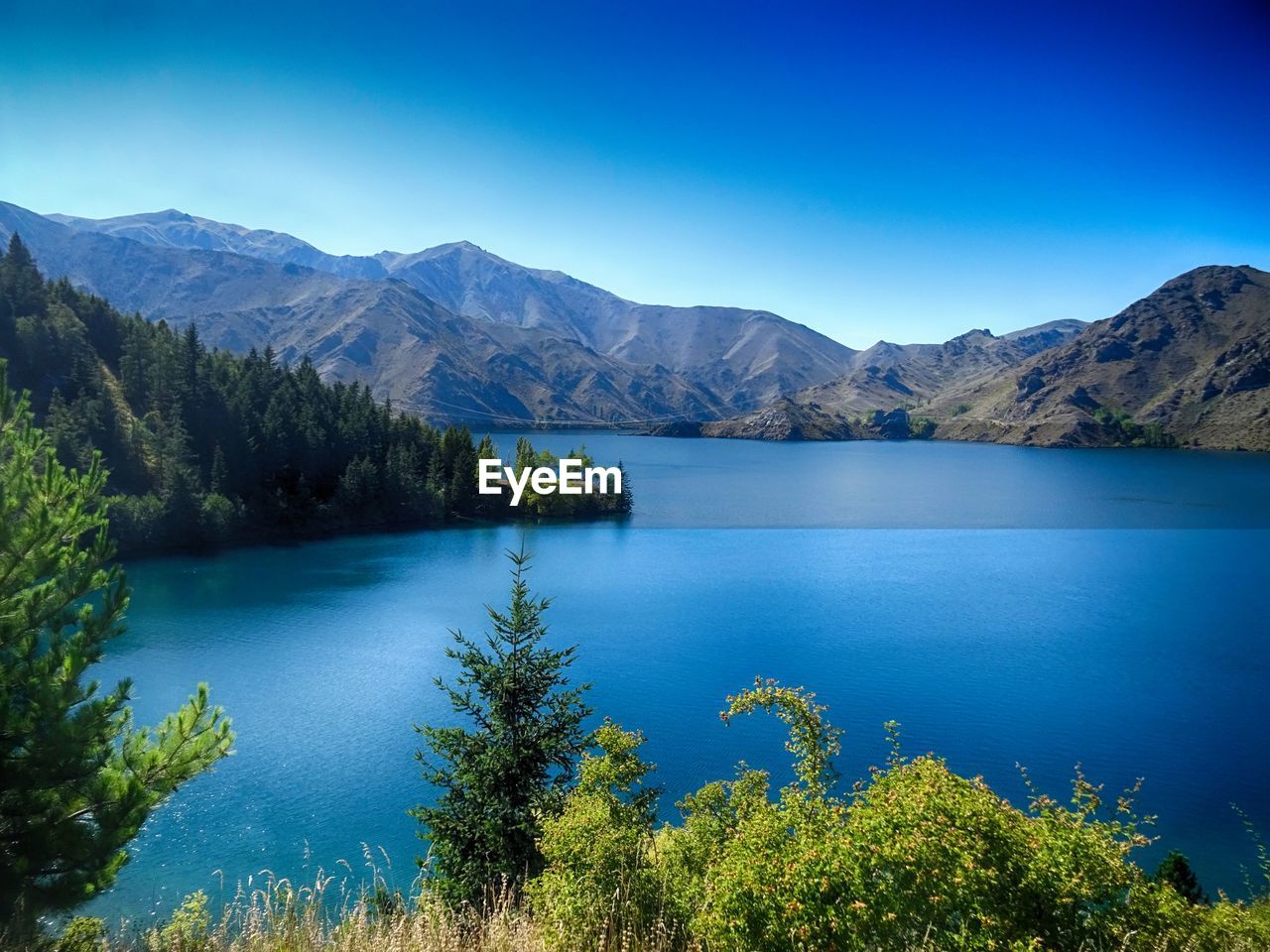 Scenic view of lake and mountains against clear blue sky