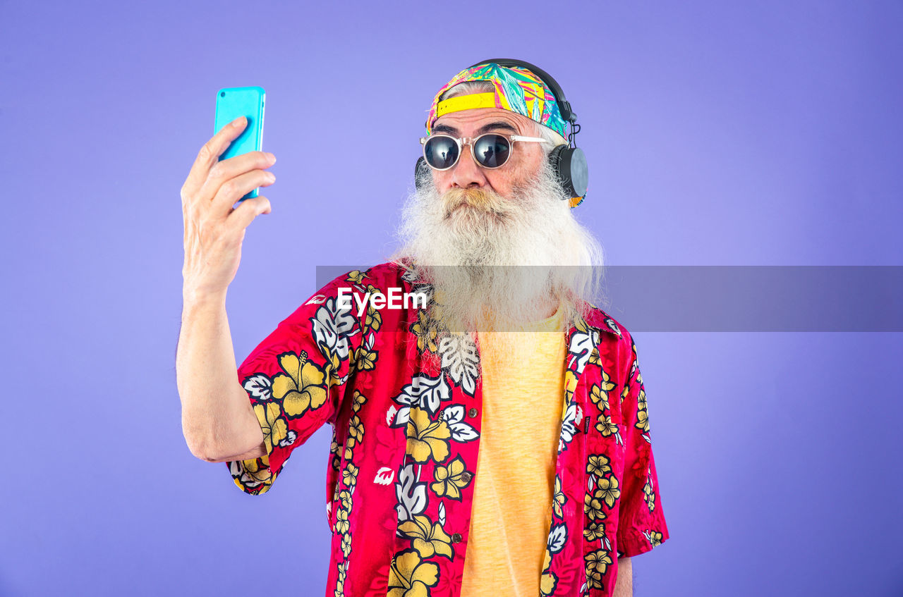 MIDSECTION OF MAN HOLDING UMBRELLA AGAINST BLUE BACKGROUND