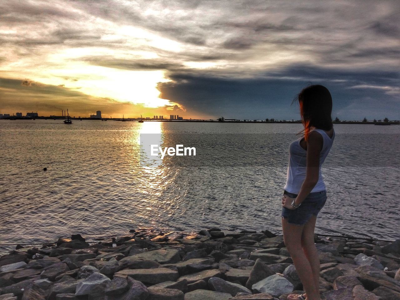 Woman standing on beach at sunset