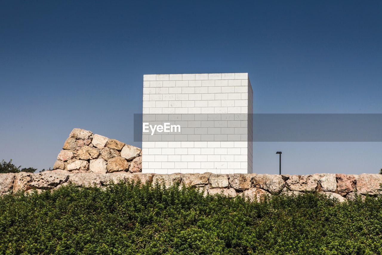 White built structure on field against clear blue sky