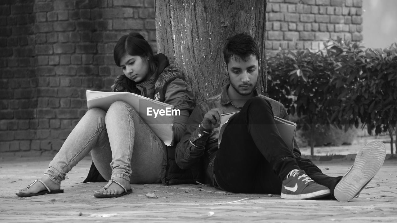 YOUNG COUPLE SITTING ON WALL