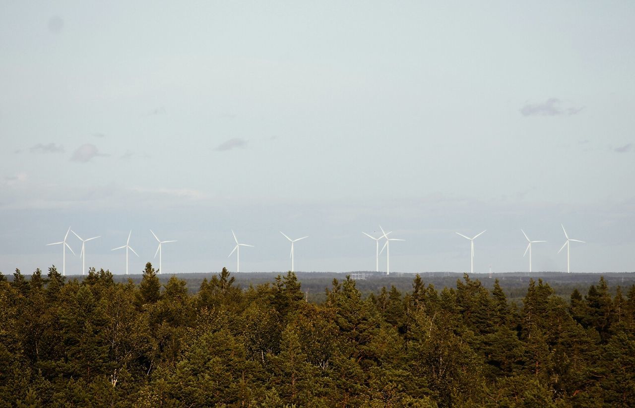 Landscape with wind turbines in distance against clear sky