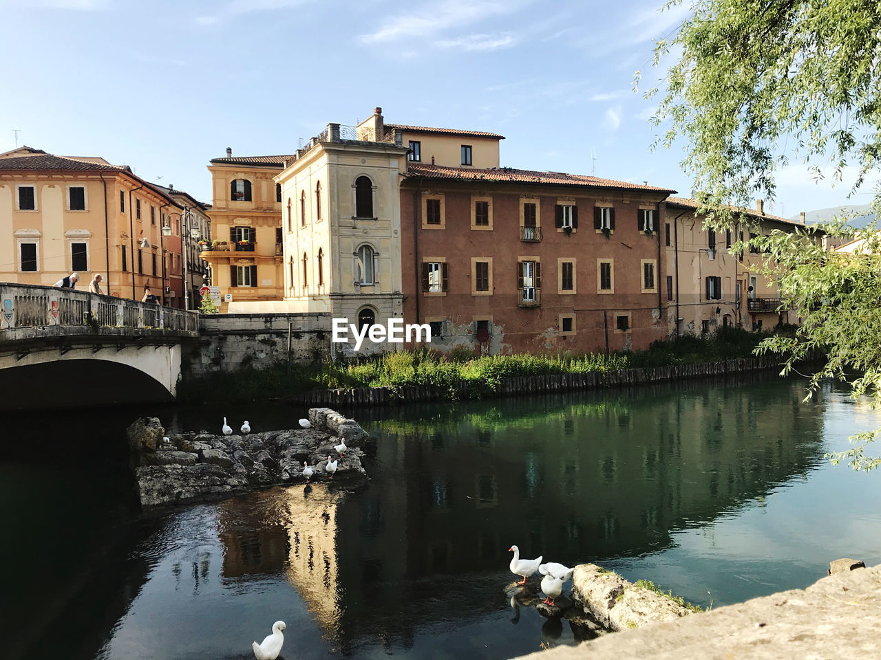 Arch bridge over river by buildings against sky