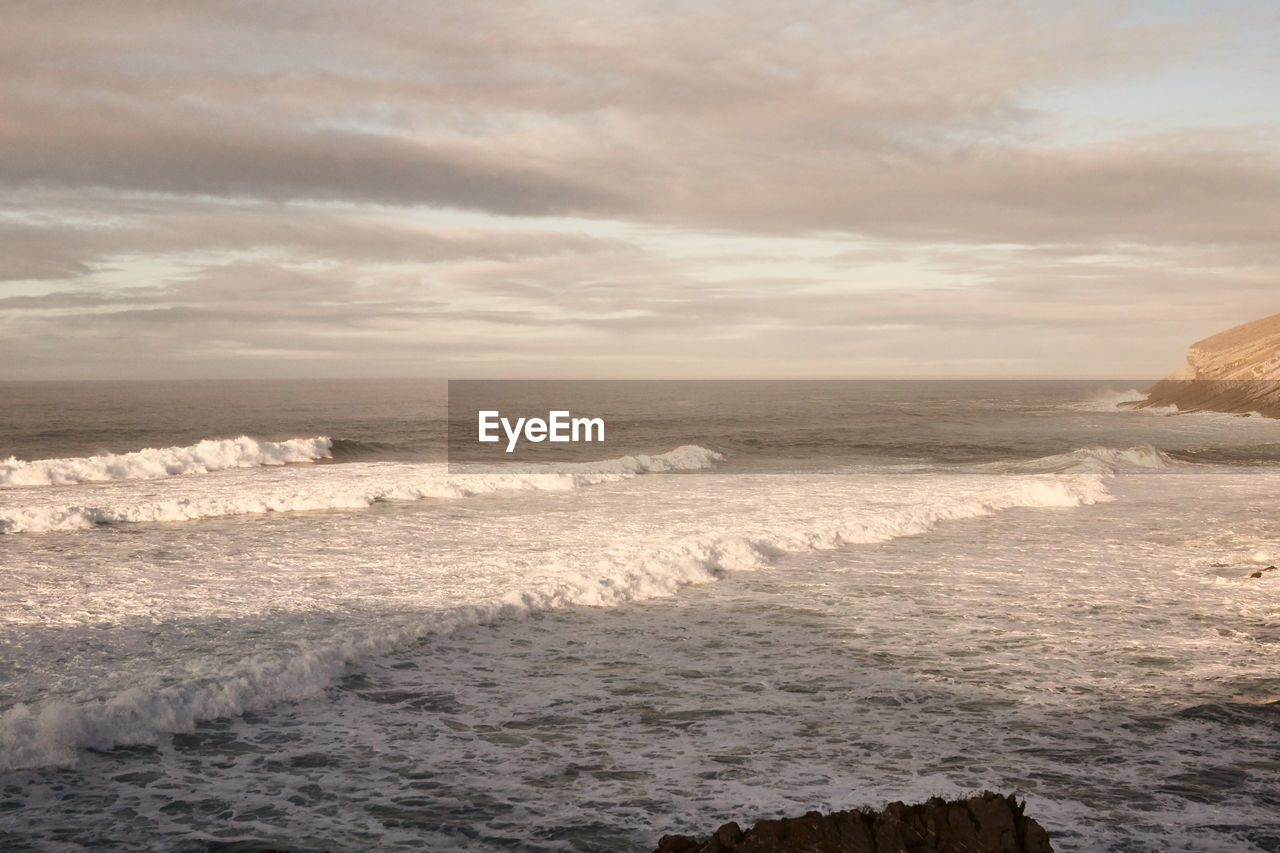 WAVES RUSHING ON SHORE AGAINST SKY