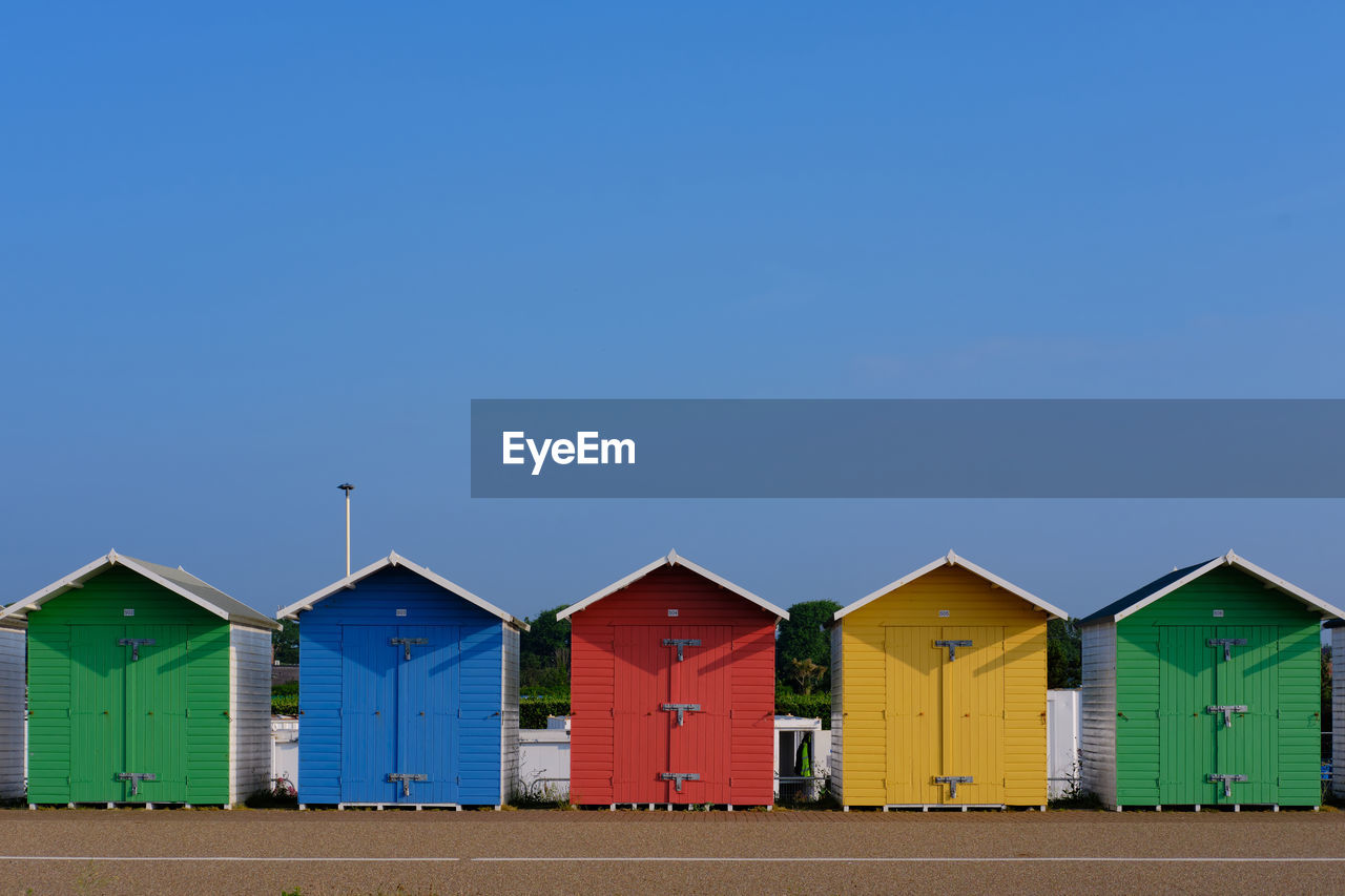 Multi-coloured beach huts in eastbourne beneath a clear blue sky in the summer