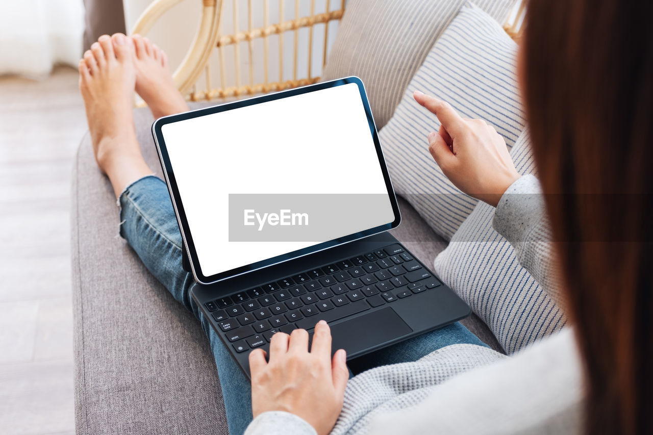 midsection of woman using digital tablet while sitting at home