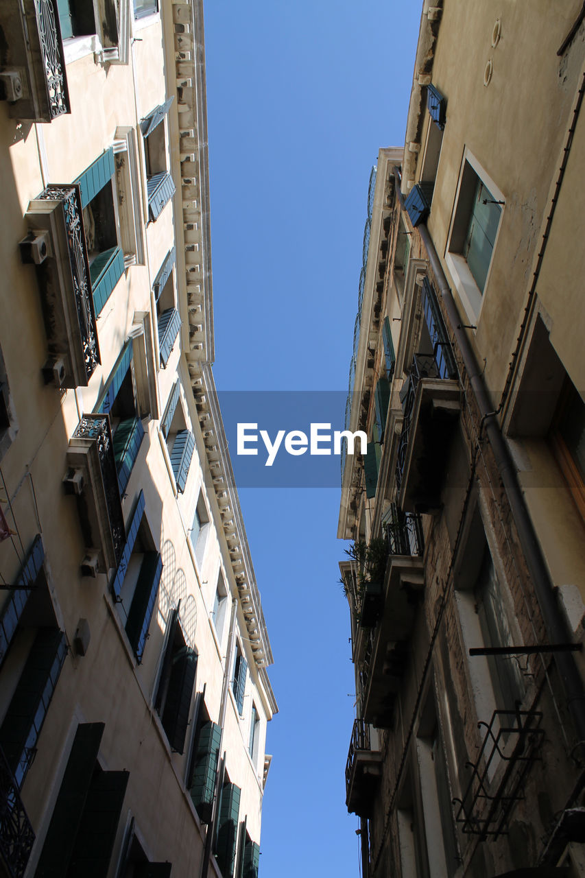 Low angle view of buildings against clear blue sky