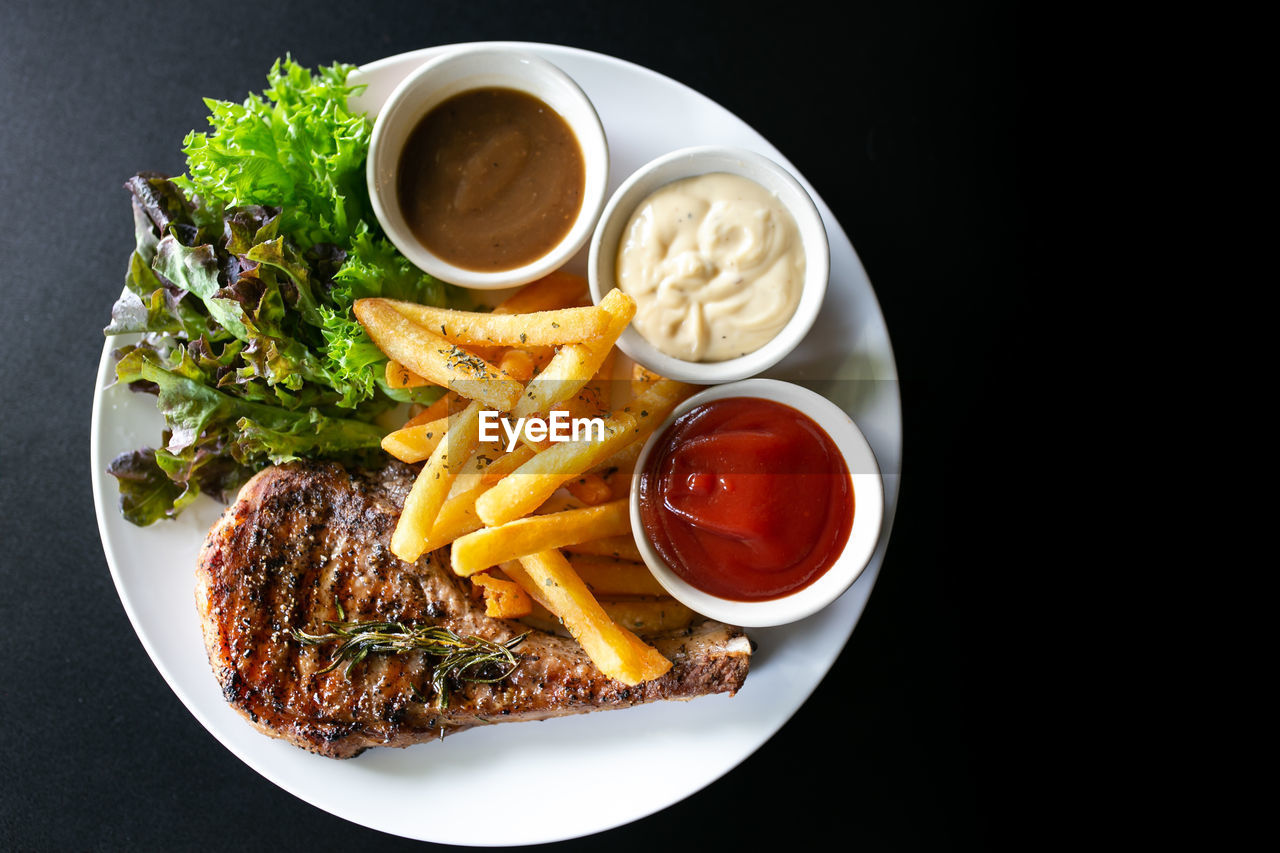 Grilled meat, porkchops steak with pepper sauce and salad.