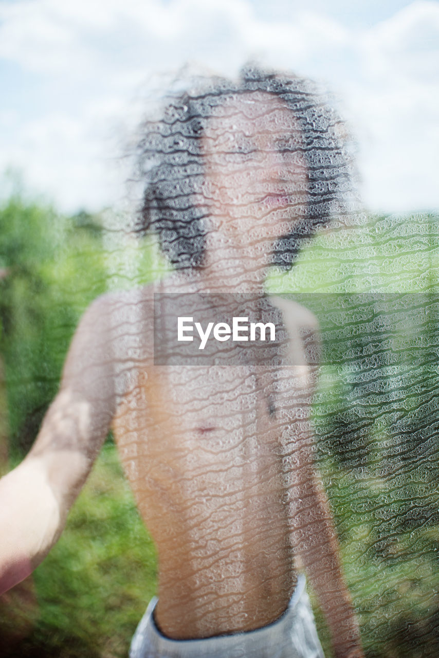 Shirtless man seen through white fabric