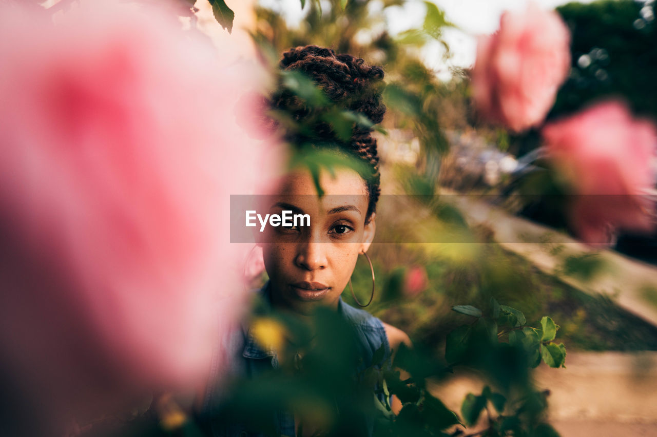 CLOSE-UP PORTRAIT OF YOUNG WOMAN WITH PINK LEAVES