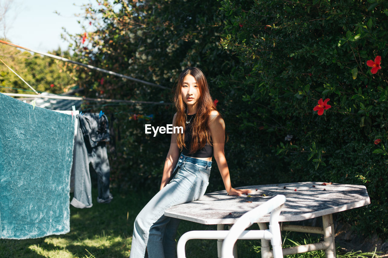 Portrait of young woman against plants in backyard